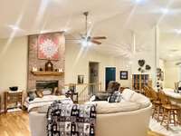 Living Room with fireplace with gas logs vaulted ceiling recessed lighting with ceiling fan; hardwood flooring backs up to the Kitchen Bar Top for seating overlooking the custom Kitchen.