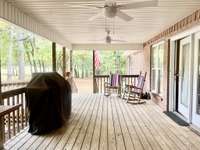 Large covered deck with vinyl siding ceiling with ceiling fans and ramp overlooking backyard with barn & chicken coop with electricity; Creek & fish pond on property