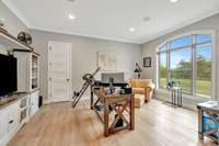 Bright home office with large arched window, built in custom cabinets, and scenic views of the outdoors.