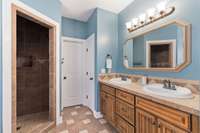 Primary bathroom with double vanity, fully tiled large shower that compliments the design of the tile  on the floor, linen closet and private water closet.
