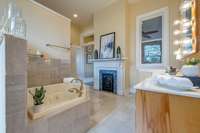 Primary bath with fireplace, dual vanities, separate soaking tub and shower, and dressing table.