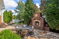 Large yard with a brick fireplace and stone patio.