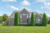 The rear of this home is accented with arborvitae and the huge backyard is level.