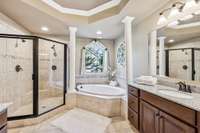 The primary bath features an oversized walk-in tiled shower, a garden tub, accented with columns, and tile flooring.