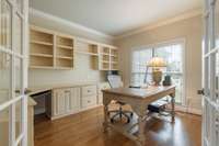 Office area with french doors, and custom built in cabinets and shelving.