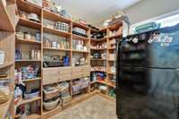 Enormous walk-in pantry with custom built-ins~This was the original laundry room~W/D outlets are behind the refrigerator~Steps from the 3 car garage make grocery/household goods unpacking a breeze.