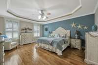 Primary bedroom is located in the back right corner overlooking the treelined backyard~Trey ceiling and plantation shutters add to the peaceful atmosphere.