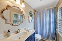 Bedroom 3's private bath has raised height painted vanity, custom mirror and tub/shower combiniation~Window with plantation shutters provides natural light.