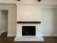 Partial white brick and shiplap gas fireplaced with cedar mantle.