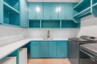 Upstairs laundry room with custom cabinets providing ample storage.