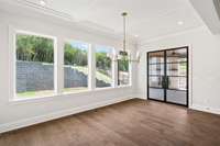 Dining room has an abundance of light from all of the windows and beautiful black iron door. Notice the picture frame trim ceiling.