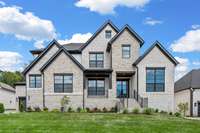 This front elevation offers a stunning mixture of brick and stone in addition to black windows and black iron door.