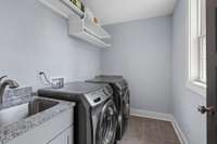 Spacious laundry room with storage shelves and a sink