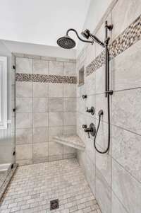 Oversized tile shower with shower head plus handheld shower head along with corner seat