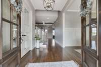 Double doors invite you into a wide entry hall with solid hardwood floors and shaker style wainscotting.