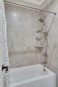 This tub and shower is tiled and has a hand sprayer with the shower head.