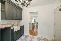 Custom tile flooring, leather cabinet pulls, and a farmhouse sink shape this space.