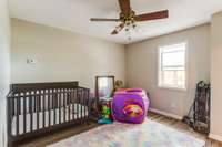 Separate den or playroom downstairs with laminate flooring and ceiling fan.