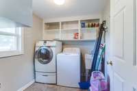 Convenient utility room with shelving and laminate flooring.  Washer & dryer do not remain.