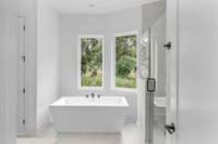 Picture windows over the tub that look out to the natural green space.