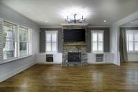 Large open living room with built in storage and a stacked stone fireplace.