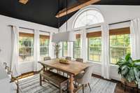 Vaulted dining room with beams and countless windows offers views of the private and tree-lined backyard.