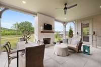 Covered back porch features a fireplace, ceiling fan, & recessed lighting