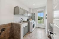 Impressive laundry room with custom cabinets, folding area & tile dog wash