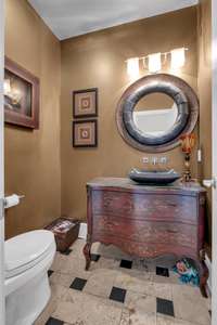 This fully custom 1/2 bath on the first flood has travertine tile and a bow-front chest as the base for the vanity.