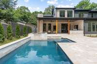 Pool and spa with travertine surround, covered porch with fireplace and outdoor kitchen