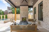 Outdoor covered porch with gas fireplace with plank ceiling and travertine floor