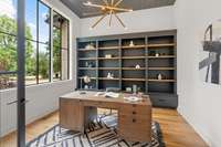 Study with built-in shelving and plank ceiling is filled with light.