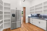 This scullery features a full refrigerator, ice maker, sink, microwave, dishwasher and bountiful pantry storage.