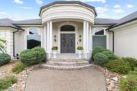 Steps of Stone lead to the extraordinary covered round porch with large circular columns that boast elegance