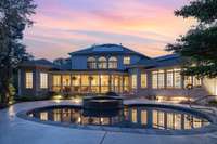 In the evening, the porch and pool glow with soft lighting