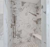 Tiles shower with multifunction showerheads and bench seating.