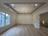 Stunning Game Room with a tray ceiling-wood trim, wet bar, French doors, storage closets and half bath *this home is under construction photo taken 5/19/24