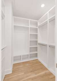 Well-sized primary closet featuring built-in drawers and multiple hanging spaces.