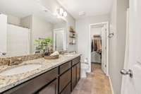 The primary bedroom has a very large bathroom with tile floors and double vanity sinks. These sinks have granite countertops.