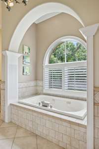 The Millwork and Tile design around this Arched Alcove make it the perfect setting for a relaxing soak. It has natural light coming through the Plantation Shutters of the Arched Window.