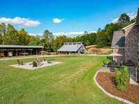 Left side Rear of Home showing the Firepit Area, Patio, Equpment storage building and Large Barn.