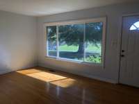 Living room with Hardwood Floors and large window overlooking the park like setting.