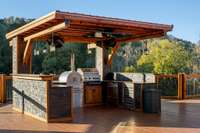 This outdoor kitchen is phenomenal: built-in pizza oven, gas grill, wine cooler, undercounter refrigerator/freezer drawers, beer keg with built-in tap, sink, lg screen TV that recesses under cover, stone siding and granite snack bar/countertops.