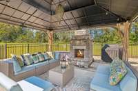 Step into this inviting covered outdoor seating area with ample space for entertaining. At the heart of this area is a charming wood-burning fireplace, perfect for cozy evenings spent outdoors making this a space for every season.