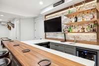 A view of the bar with cabinets and mini wine cooler.