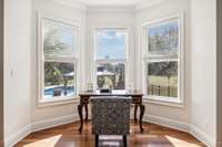 The cozy nook in the primary bedroom can be used as an additional private work space. With sweeping views of the back lawn and built-in pool.