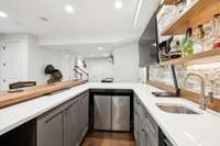 Another view of the bar with raised wood counter top and coordinating shelving and mini sink.