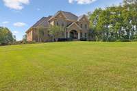 The lush green front lawn stretches gracefully across the front of the property offering an impressive view the moment you arrive.