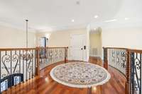 The upper level foyer is surrounded by intricate iron railings. Reach this space by stair or by elevator. The elevator serves all three levels.