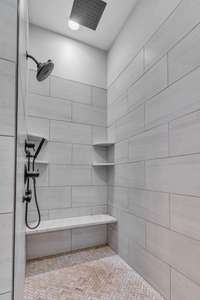 A luxurious owner's bath featuring an oversized tiled walk-in shower with a rainhead and showerhead plus 2 body wands for a spa-like experience. The 5-position switch valve allows for customized water flow, enhancing relaxation.